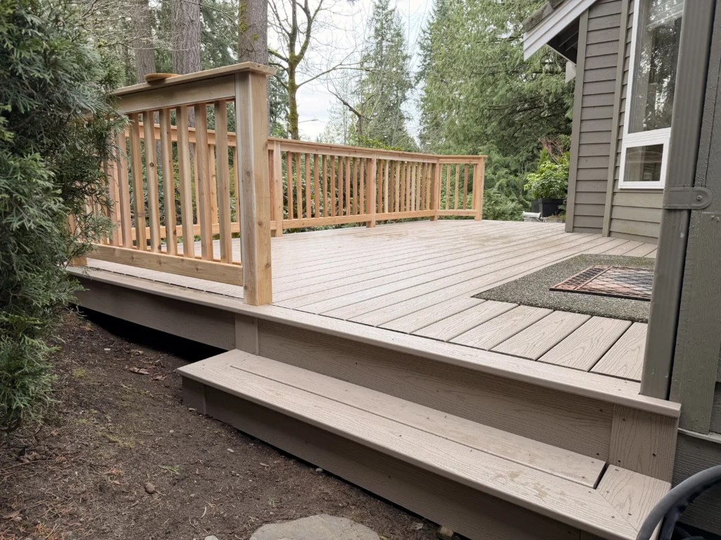 A New Composite Deck Installation In Mill Creek Wa Features Durable Taupe Planks And A Classic Wooden Railing.
