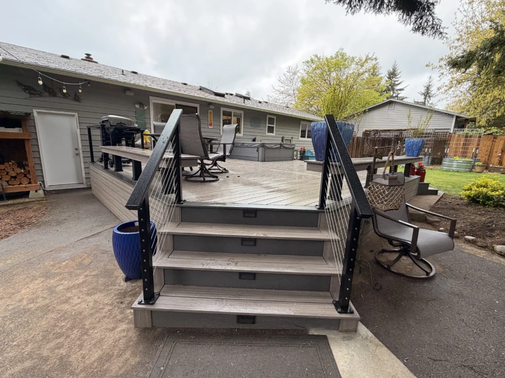 Front View Of Grey Steps With Black Cable Railings Leading Up To A Finished Composite Deck Installation In Seattle Wa.