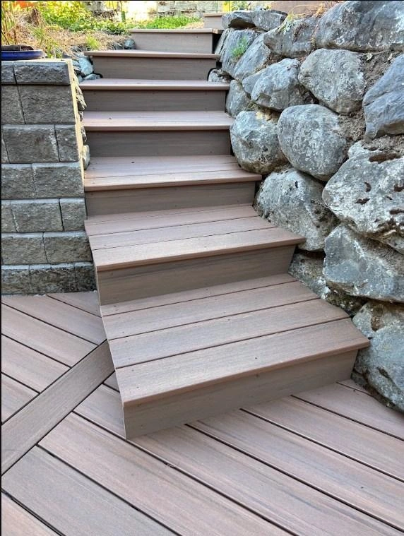 Olympic Decks View Looking Up New Durable Composite Steps Built Between A Stacked Block Wall And A Boulder Retaining Wall, Replacing Old Wood.